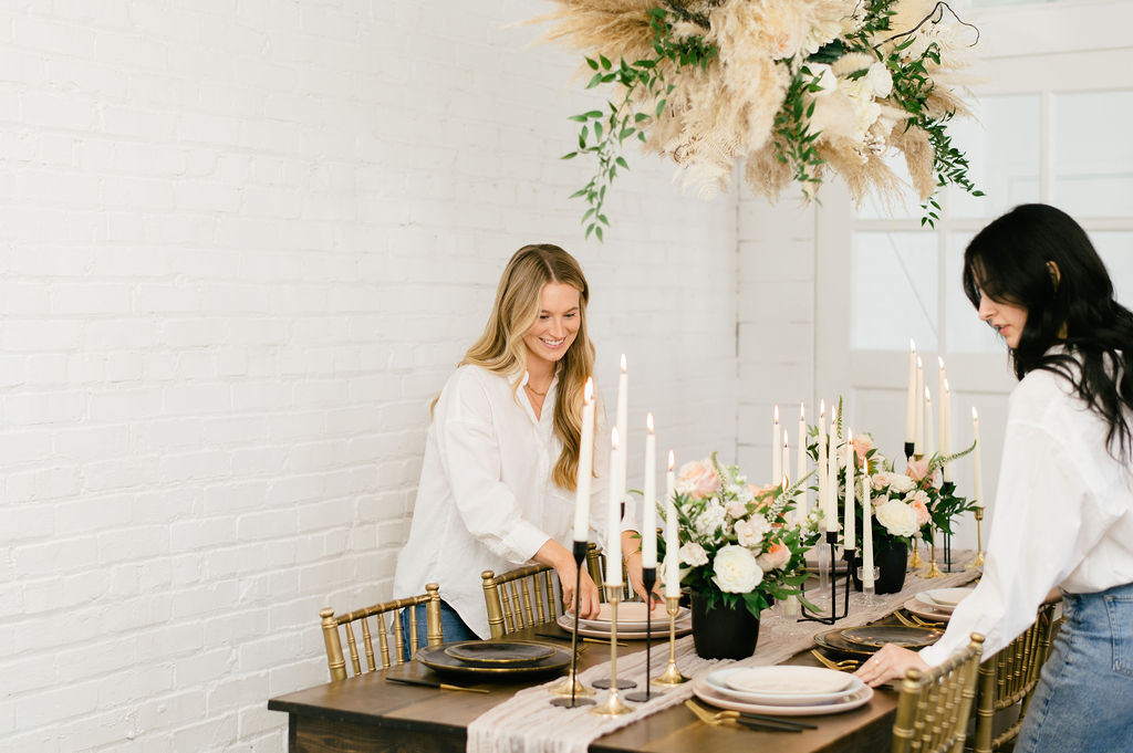 Two wedding planners setting a table.